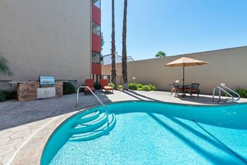 A small pool with a slide and a sun umbrella.